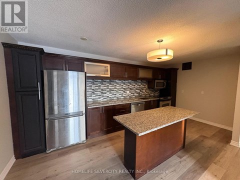 A kitchen area with a refrigerator, microwave, and a countertop.
