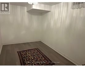 A room with a rug on the floor and a chandelier hanging from the ceiling.