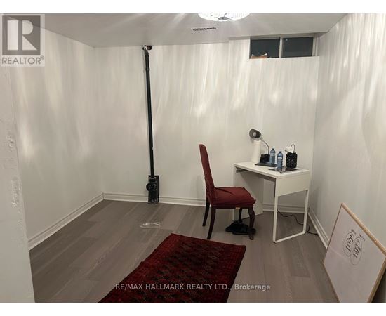 A room with a red chair and a desk with a white chair and a sign that says RE/MAX HALLMARK REALTY LTD Brokerage.