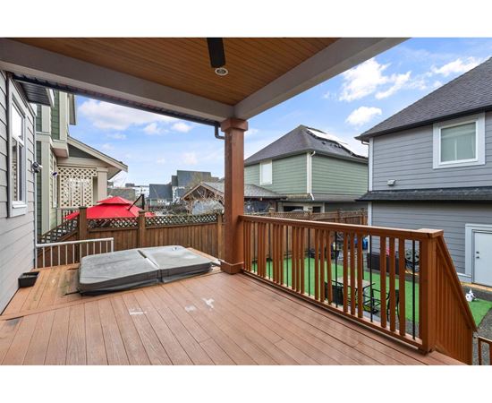 A wooden deck with a hot tub and a red umbrella.