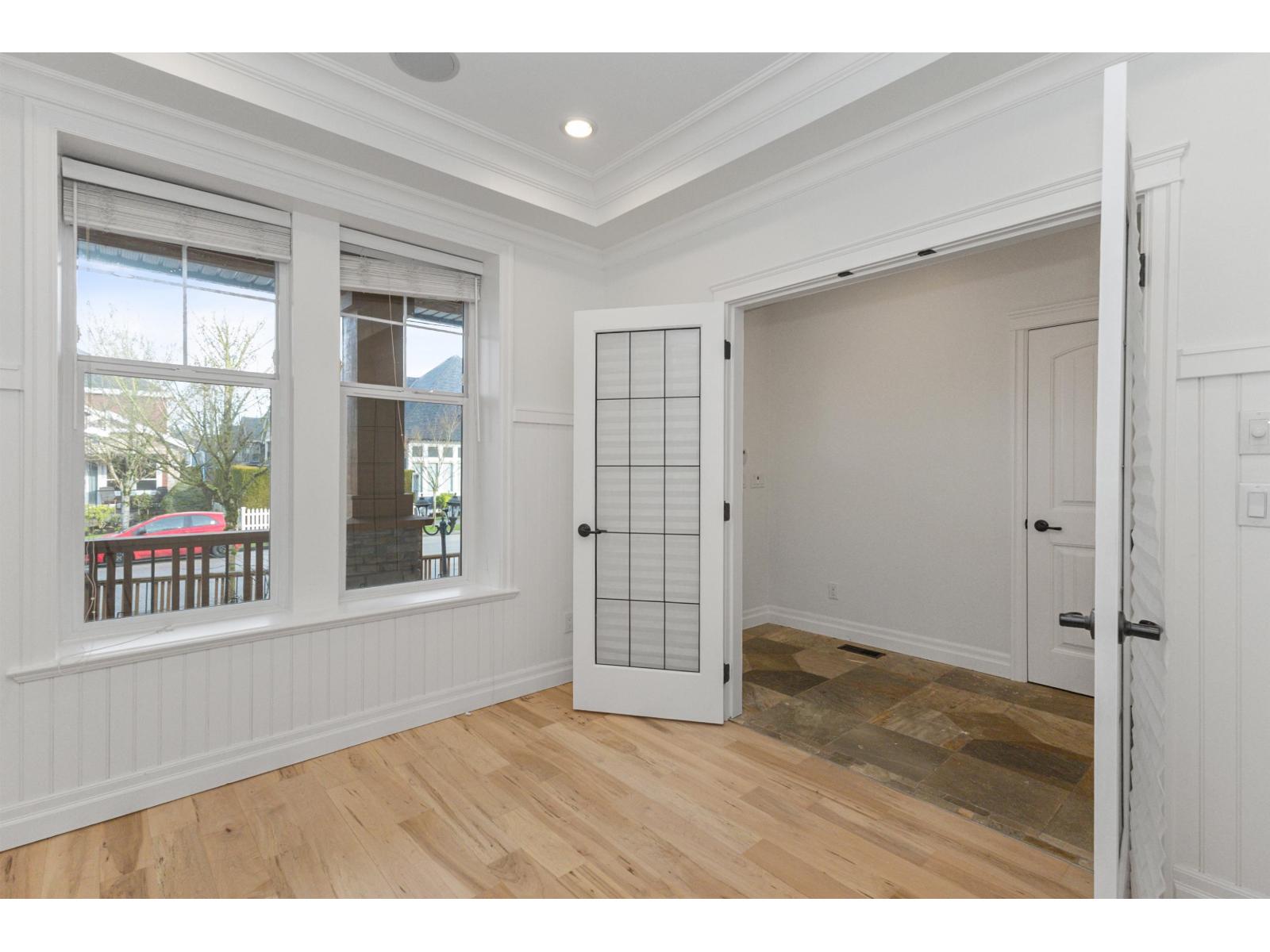 A room with a white door and a window with a view of a deck and trees.