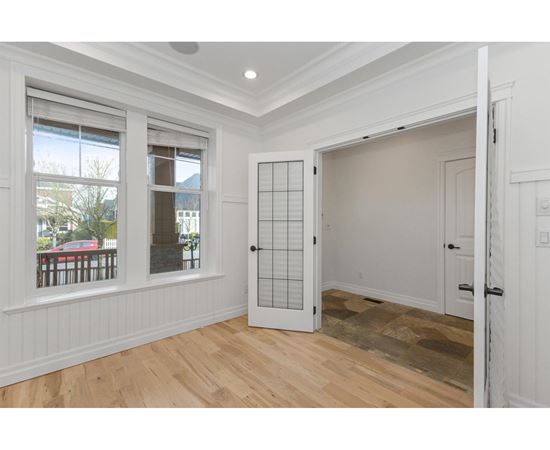 A room with a white door and a window with a view of a deck and trees.