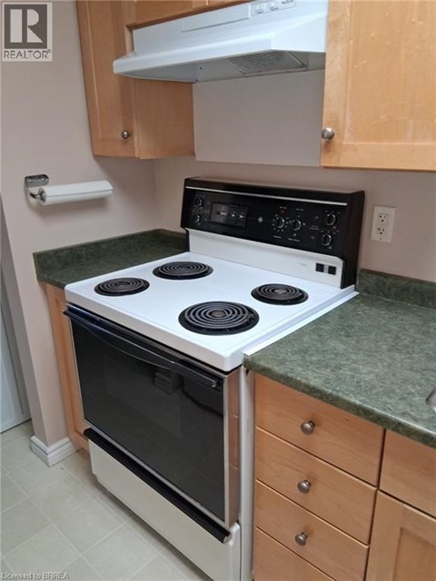 A white stove top oven with four burners and a black control panel is on a kitchen counter.