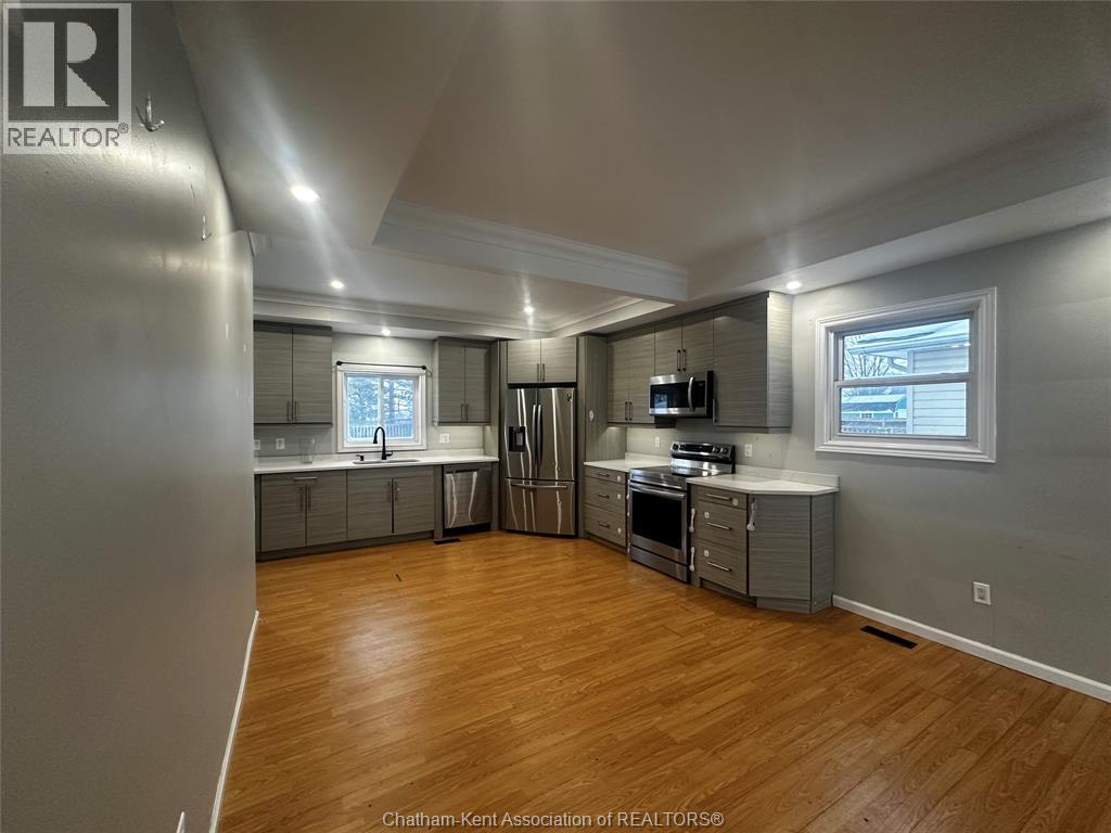 A spacious kitchen with wood flooring and stainless steel appliances.