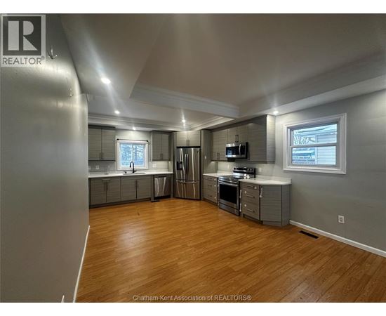 A spacious kitchen with wood flooring and stainless steel appliances.