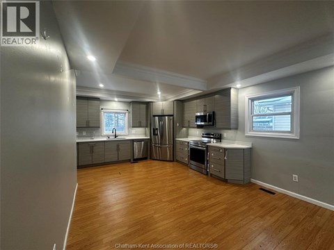 A spacious kitchen with wood flooring and stainless steel appliances.