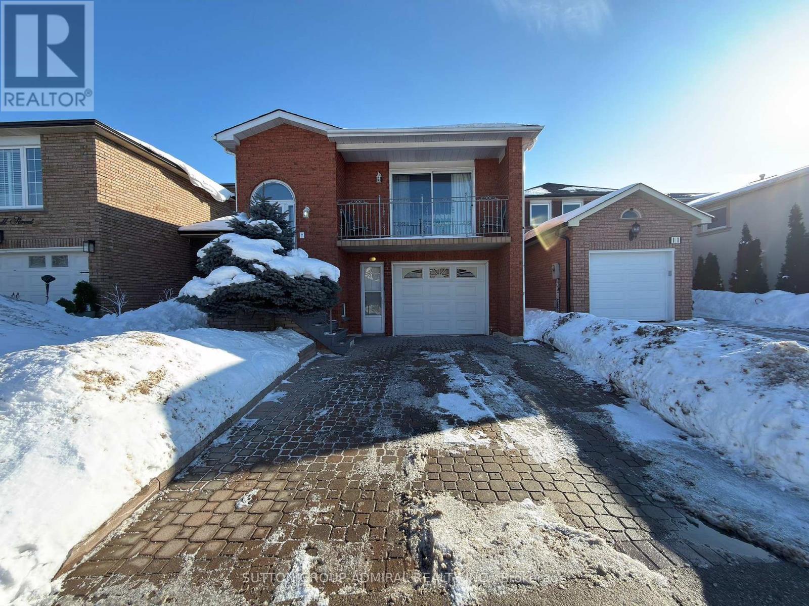 A house with a snow-covered driveway in front.