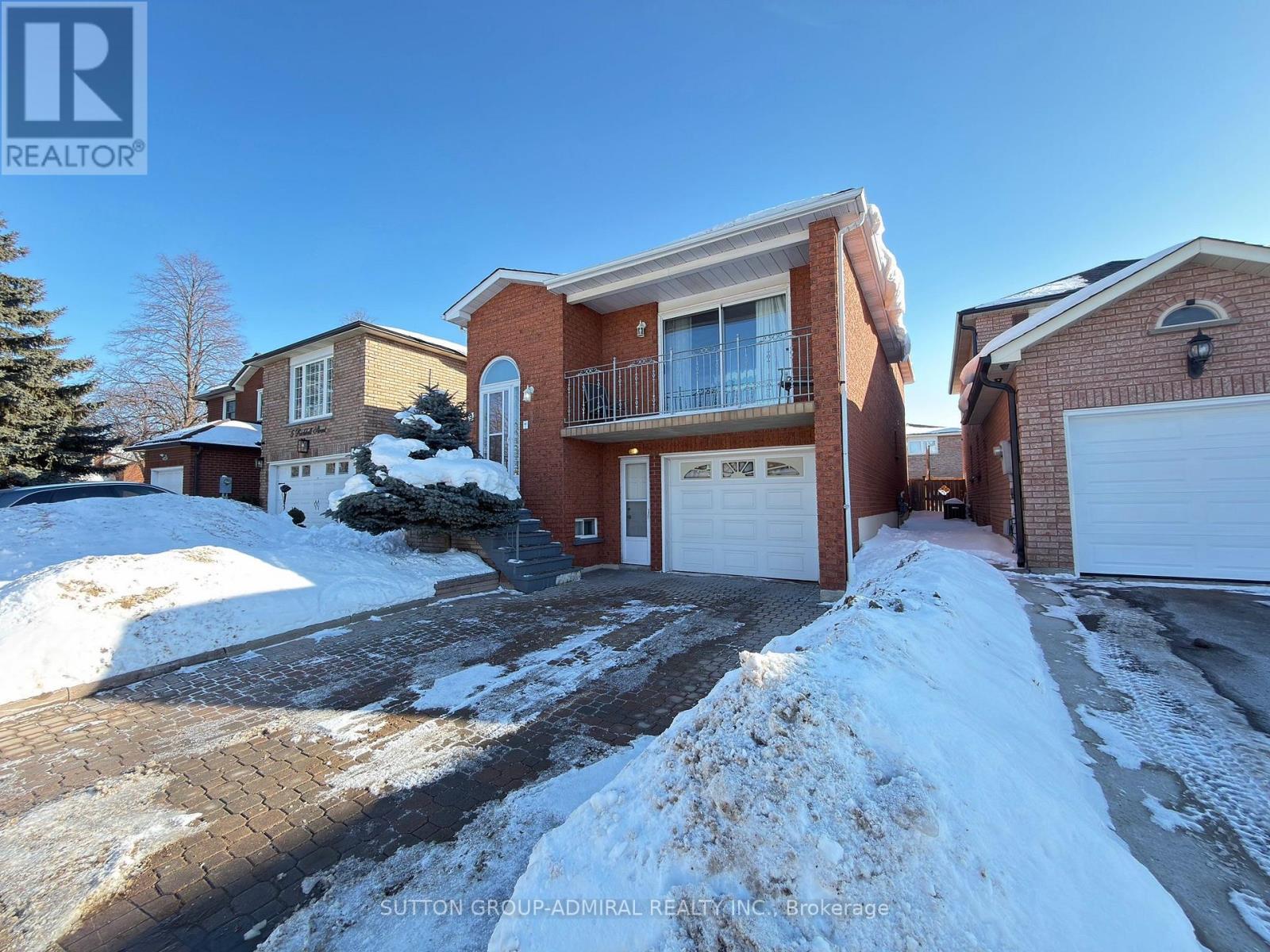 A house with a snow-covered driveway in front of it.