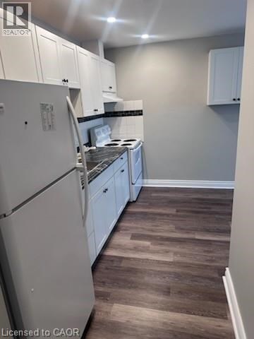 A kitchen with white cabinets and a white fridge.