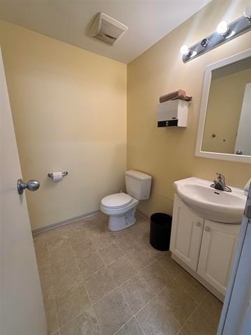 A bathroom with a toilet, sink, and mirror.