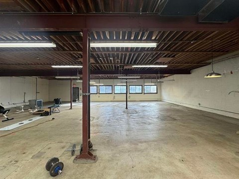 A large, empty room with a wooden ceiling and a red pillar in the center.