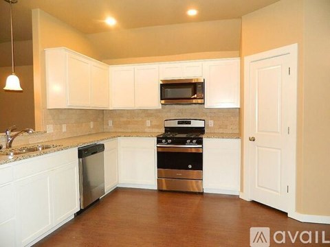 A kitchen with white cabinets and a wooden floor.