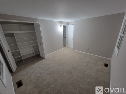 A spacious room with a staircase on the left and a door on the right.