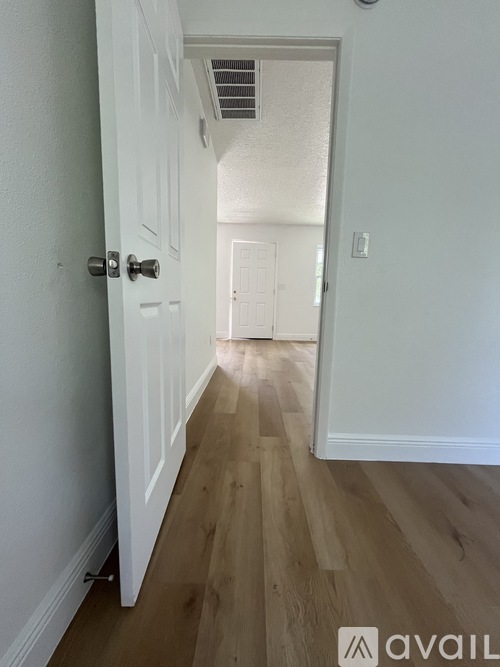 A hallway with a white door and wooden floors.