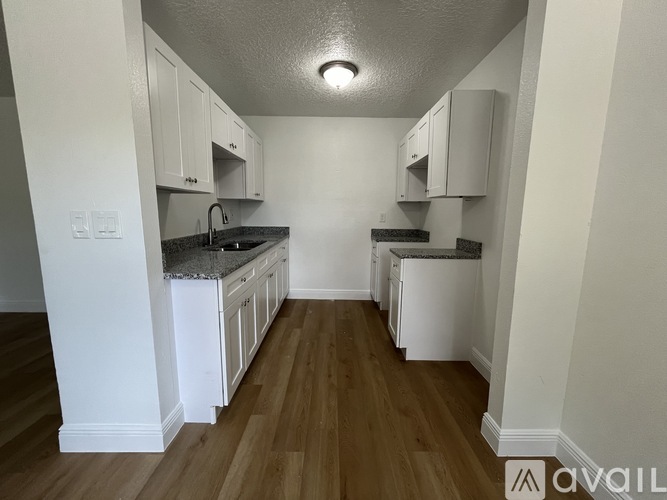 A kitchen with white cabinets and a wooden floor.
