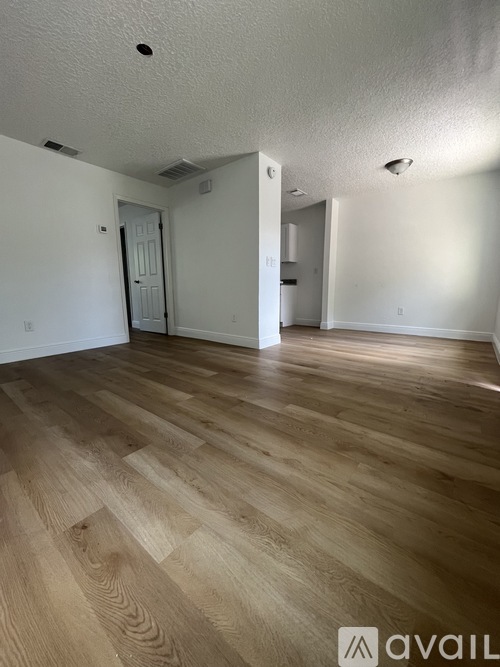 A room with wooden flooring and white walls.