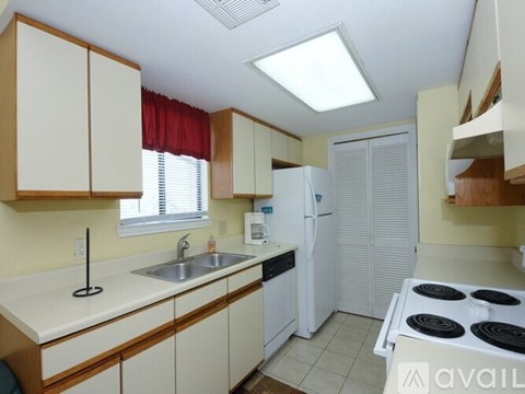 A kitchen with a white stove top oven, white fridge, and white counter tops.