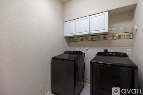 Two black microwaves are on a shelf in a kitchen.