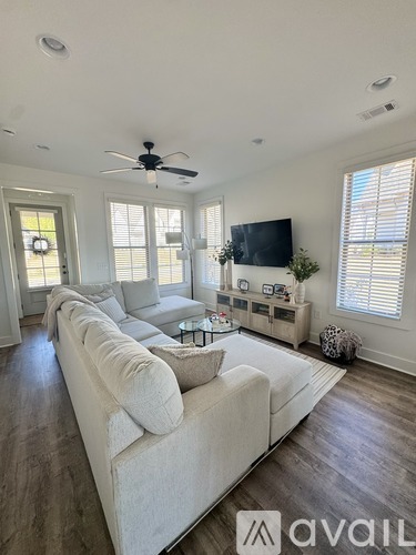 A living room with a white couch and a flat screen TV mounted on the wall.