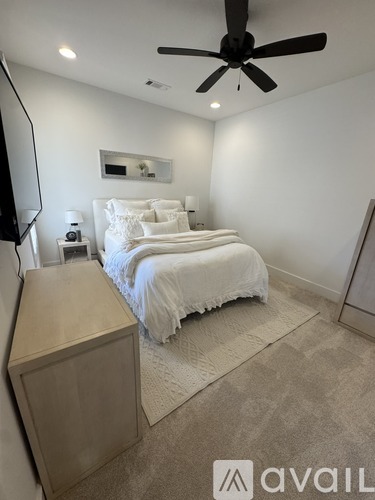 A bedroom with a large bed and a ceiling fan.
