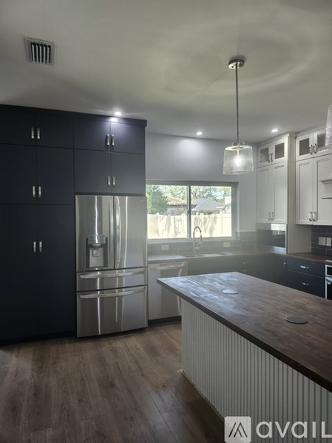 A kitchen with black cabinets and a wooden countertop.