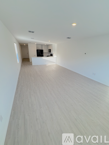 A spacious room with wooden flooring and white walls.