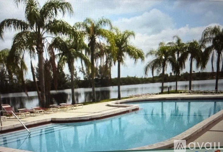 A pool surrounded by palm trees and lounge chairs.