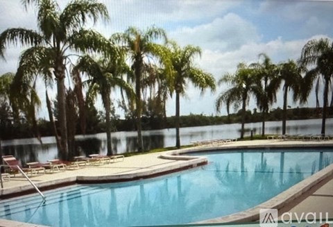 A pool surrounded by palm trees and lounge chairs.
