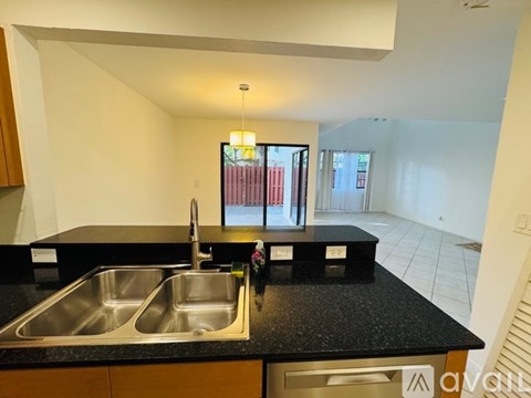 A kitchen with a black countertop and a stainless steel sink.