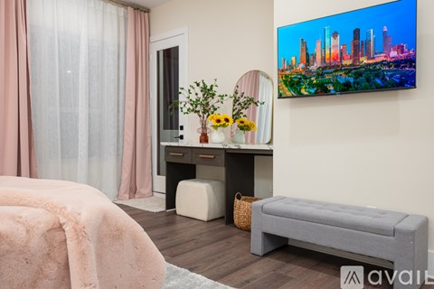 A room with a bed, a desk, a bench, and a painting on the wall.