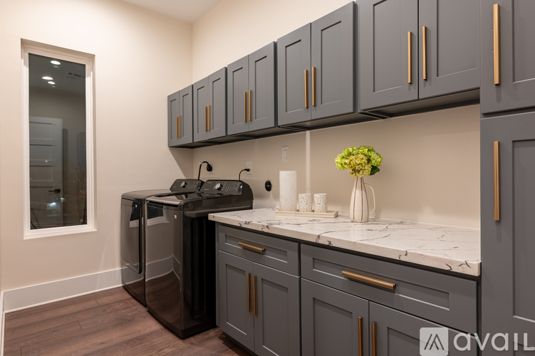 A kitchen with dark grey cabinets and a black fridge.