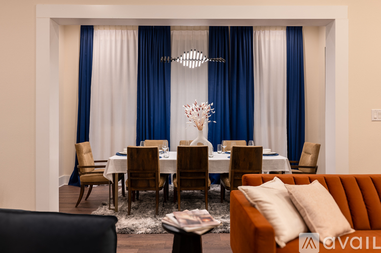 A dining room with a table set for six and a chandelier hanging from the ceiling.