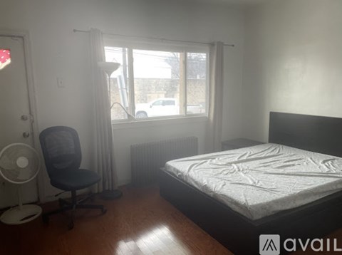 A bedroom with a bed, chair, and window.