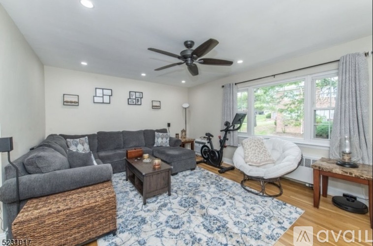A living room with a grey couch, a white chair, a coffee table, and a bicycle.