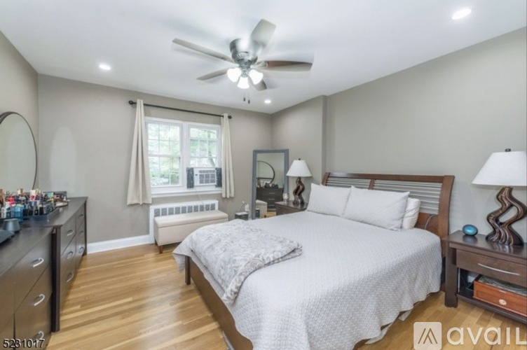 A bedroom with a large bed, a ceiling fan, and a window with curtains.
