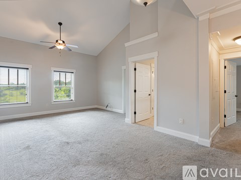 A spacious room with a ceiling fan and two windows.