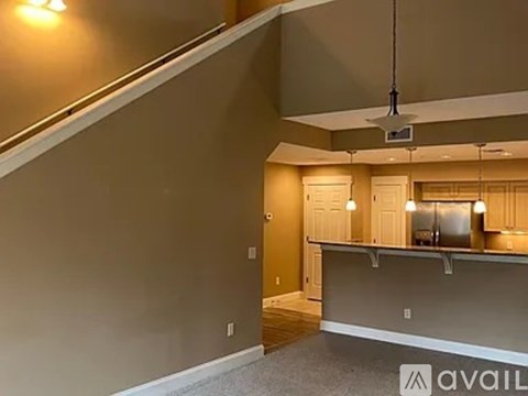 A spacious room with a bar area and a staircase.