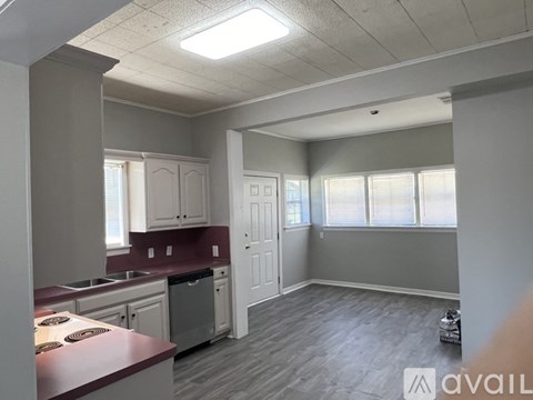 A kitchen with a red countertop and a dining area with a table and chairs.