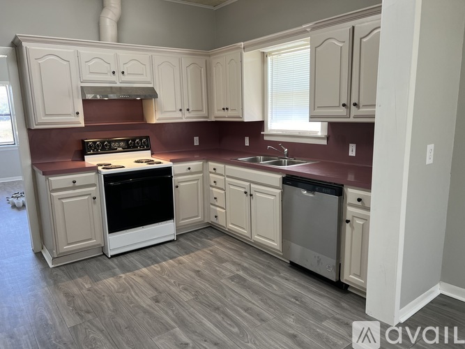 A kitchen with a white stove top oven and white cabinets.