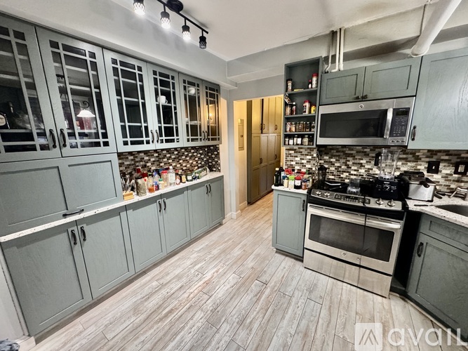 A kitchen with grey cabinets and a tile backsplash.