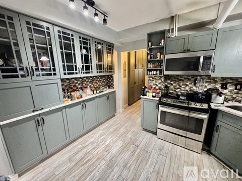 A kitchen with grey cabinets and a tile backsplash.