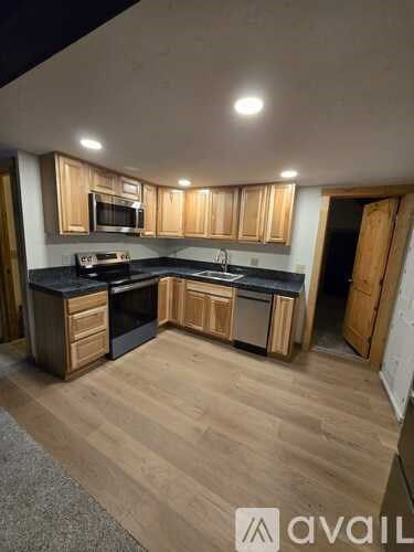 A kitchen with wooden cabinets and black countertops.