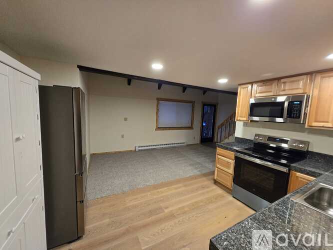 A kitchen with wooden cabinets and a black refrigerator.