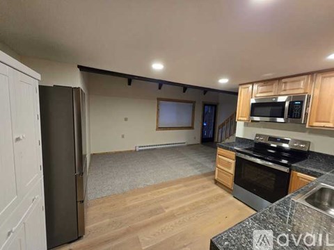 A kitchen with wooden cabinets and a black refrigerator.