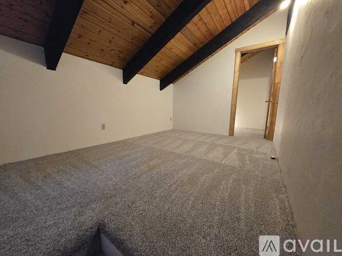 A room with a wooden ceiling and carpeted floor.