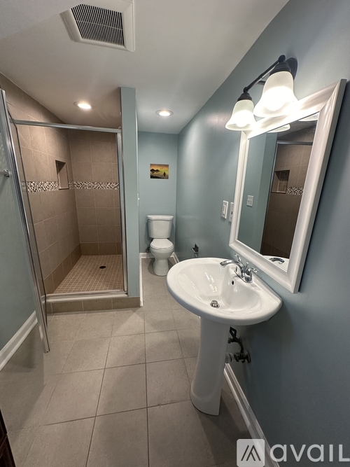 A bathroom with a sink, mirror, toilet and shower.