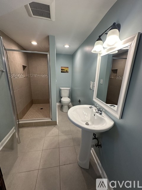A bathroom with a sink, mirror, toilet and shower.