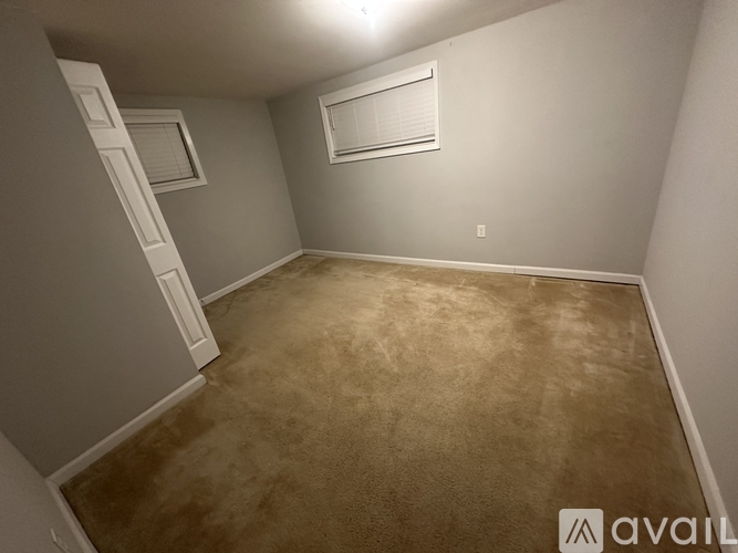 A room with a carpeted floor and a window with blinds.