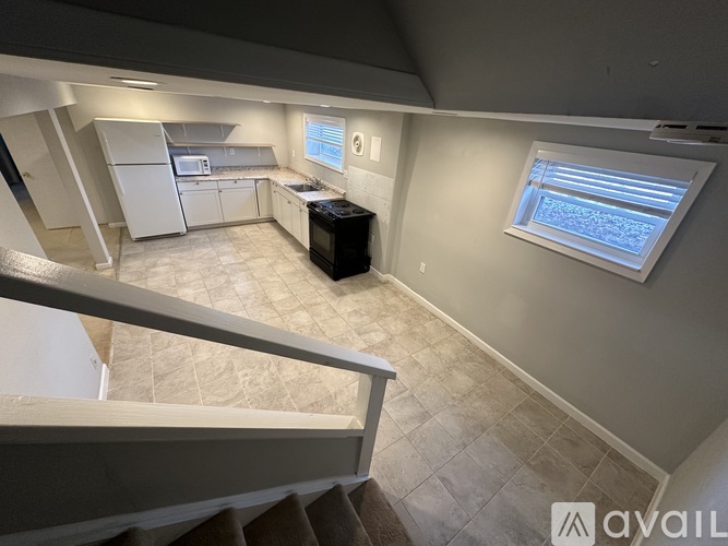 A kitchen area with a refrigerator, microwave, and a black trash bin.