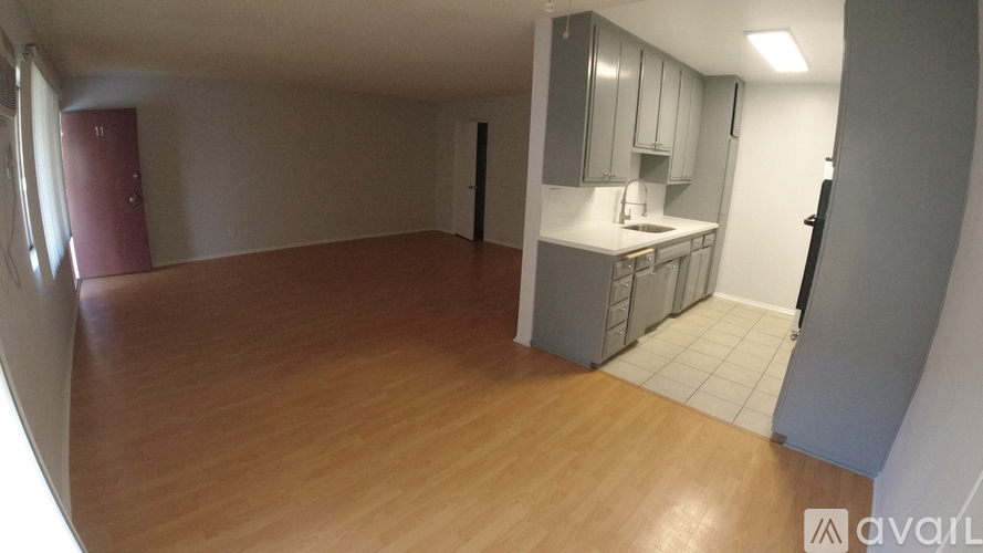 A kitchen area with wooden flooring and a red door.